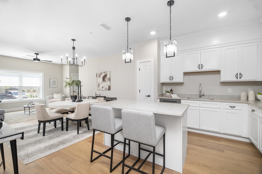 36 Old Louisquisset Pike, Unit 106 North Smithfield, RI 02896 - Photo 8 of 30 a kitchen with stainless steel appliances kitchen island granite countertop a dining table chairs and white cabinets