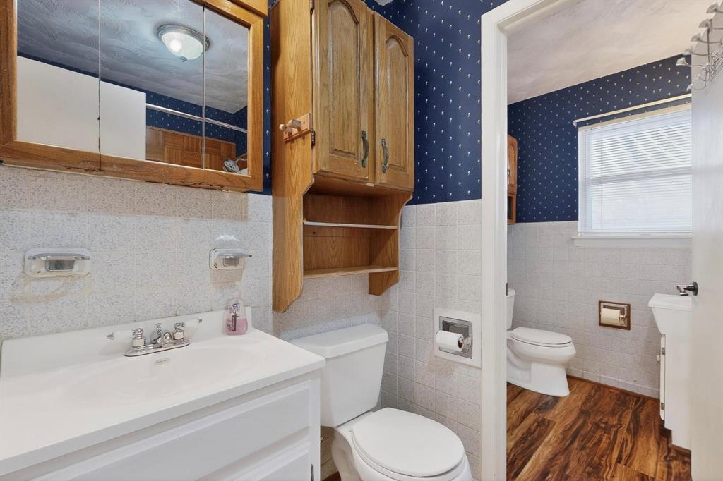 202 Senter Valley Road Irving, TX 75060 - Photo 21 of 32 Bathroom featuring a white vanity with integrated sink, chrome faucet, white tile wainscoting, and wood-finish flooring