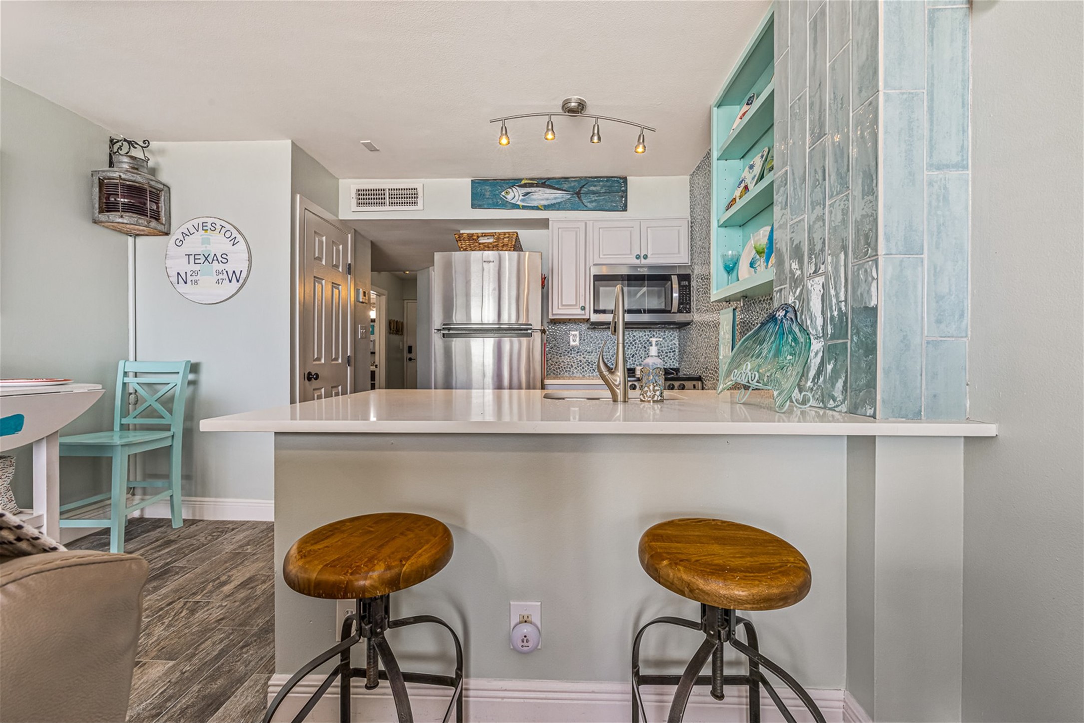 11945 Termini-San Luis Pass Road, Unit 406 Galveston, TX 77554 - Photo 16 of 26 Kitchen with a breakfast bar area, stainless steel appliances, a peninsula, dark wood-type flooring, and white cabinetry