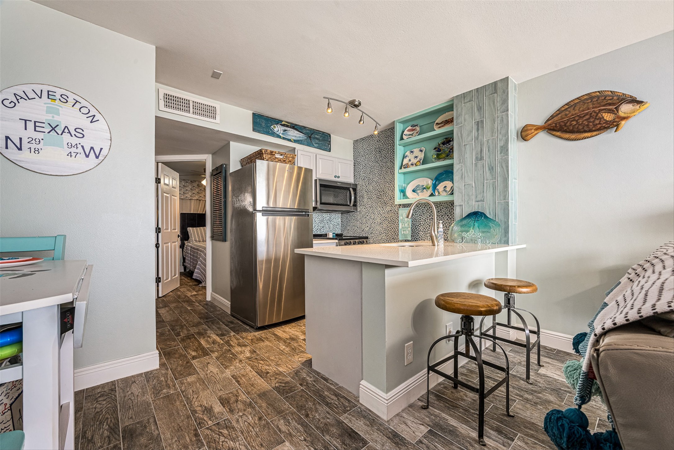 11945 Termini-San Luis Pass Road, Unit 406 Galveston, TX 77554 - Photo 17 of 26 Kitchen with white cabinets, stainless steel appliances, wood finish floors, a kitchen breakfast bar, and a peninsula