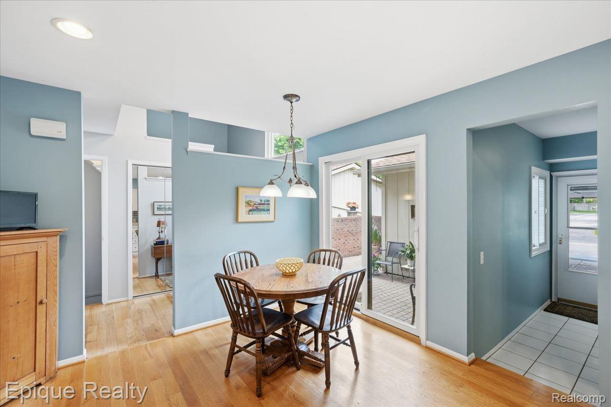 26 Kirks Court Rochester, MI 48309 - Photo 17 of 44 Dining area featuring wood-finish flooring, a sliding glass door to the exterior, a ceiling-mounted light fixture, and blue painted walls