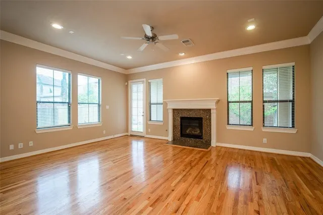 an empty room with wooden floor fireplace and windows