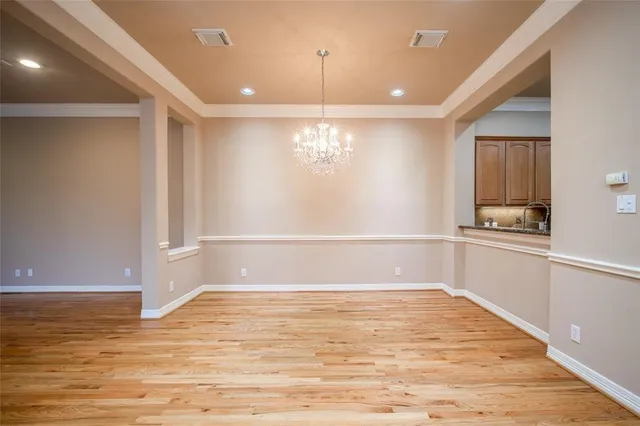 a view of kitchen and empty room with wooden floor