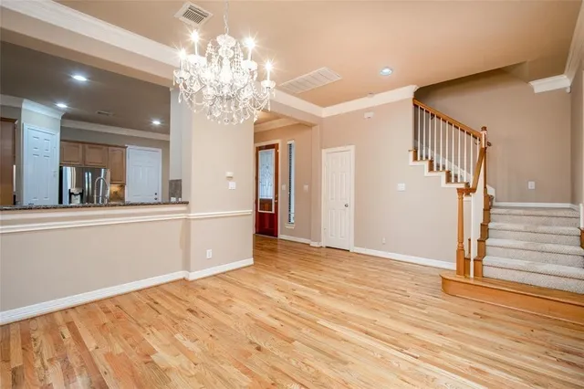 a view of a hallway with wooden floor and chandelier