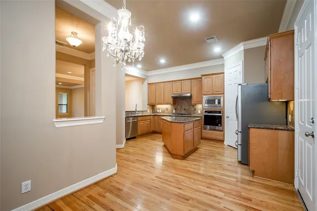 a kitchen with stainless steel appliances granite countertop a refrigerator a sink a stove and a wooden floors