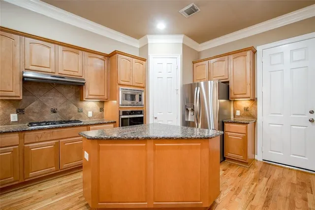 a kitchen with stainless steel appliances granite countertop a refrigerator a stove and a sink with large window