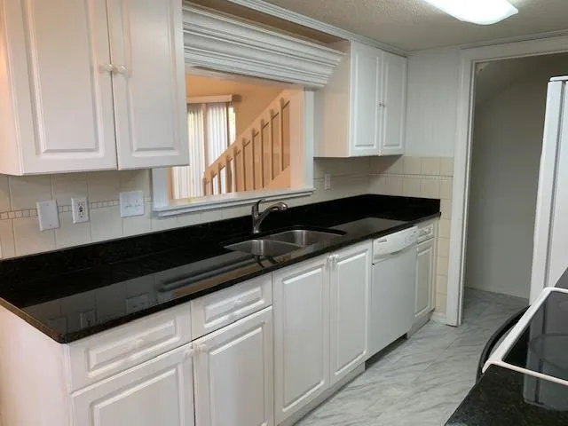 a kitchen with granite countertop white cabinets and a sink
