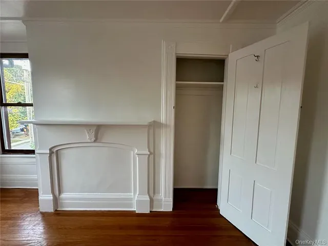 an empty room with wooden floor cabinet and windows