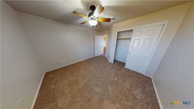 an empty room with a ceiling fan and a rug