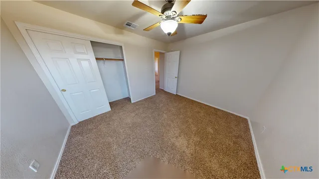 an empty room with closet and a chandelier fan