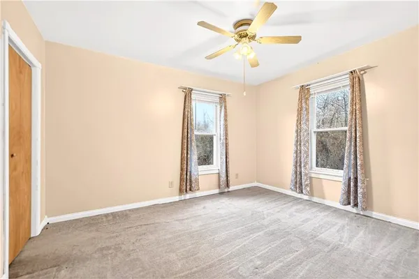 an empty room with windows and fan