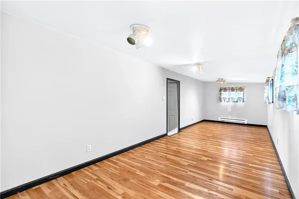 a view of an empty room with a window and wooden floor