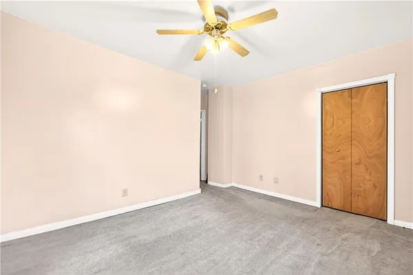 an empty room with closet and a ceiling fan