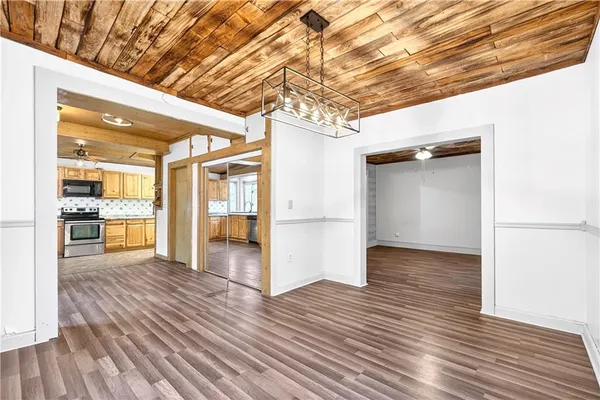 a view of an empty room with wooden floor and a kitchen