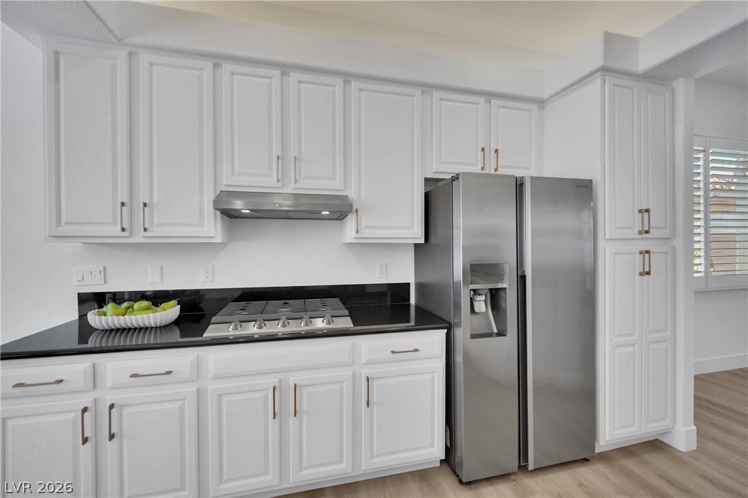 8981 Rivers Edge Drive Las Vegas, NV 89117 - Photo 20 of 69 A contemporary kitchen showcasing sleek stainless steel appliances paired with crisp white cabinetry and dark countertops.