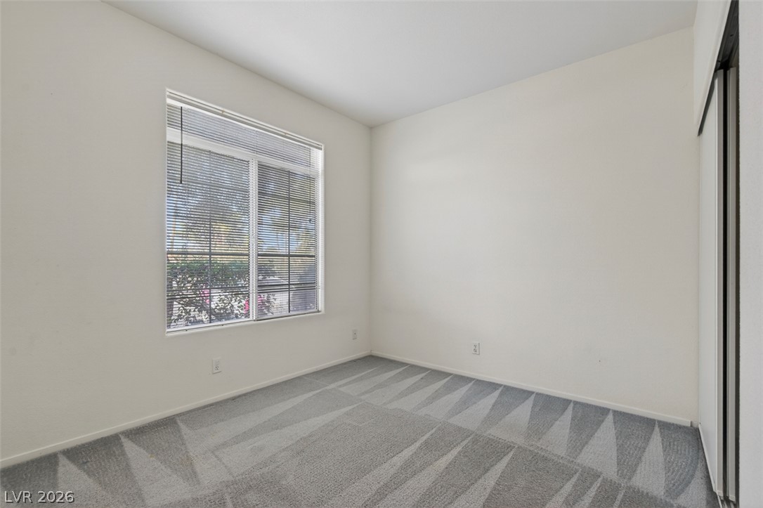 2201 Ramsgate Drive, Unit 1011 Henderson, NV 89074 - Photo 25 of 40 A window-filled bedroom with soft, patterned carpet offers a tranquil retreat.