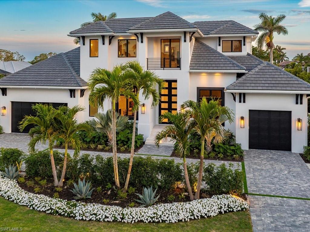 View of front facade with a balcony, decorative driveway, stucco siding, and an attached garage