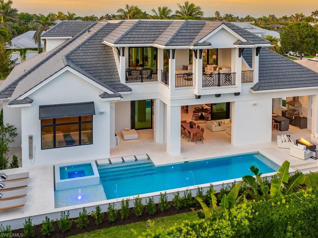 612 Binnacle Drive Naples, FL 34103 - Photo 2 of 50 Rear view of house featuring an outdoor pool, stucco siding, a tiled roof, a balcony, and a patio area