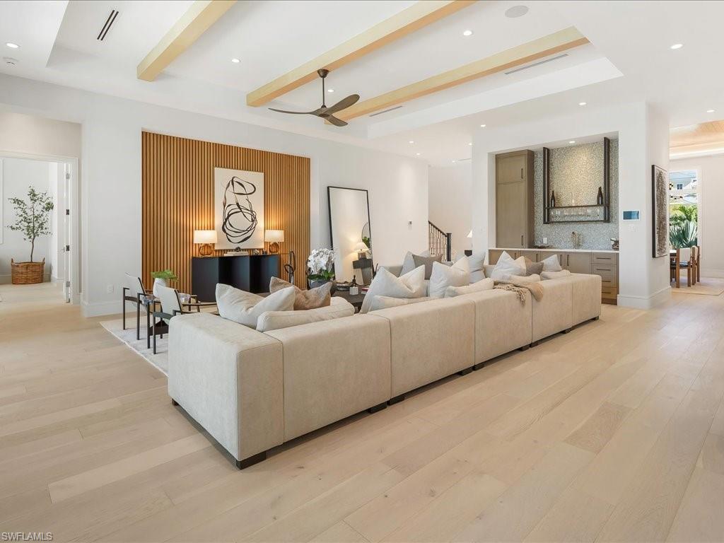 612 Binnacle Drive Naples, FL 34103 - Photo 5 of 50 Living area featuring light wood-style flooring, beamed ceiling, stairs, a ceiling fan, and a raised ceiling