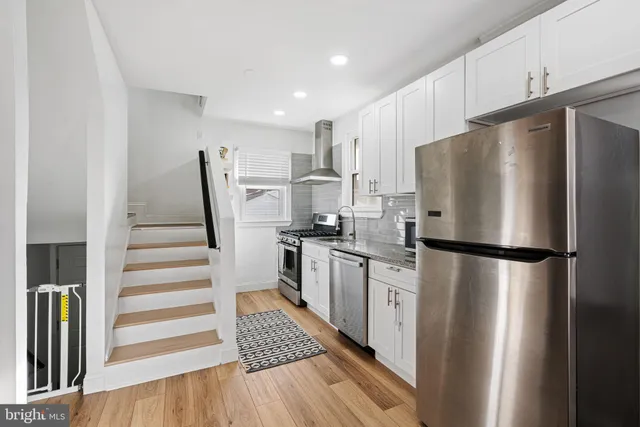 a kitchen with stainless steel appliances a refrigerator a sink and white cabinets