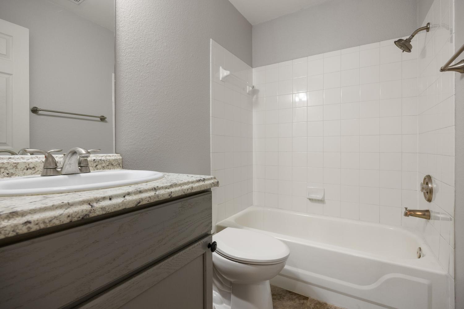 521 Britni Loop Kyle, TX 78640 - Photo 13 of 23 a bathroom with a granite countertop sink a toilet and bathtub