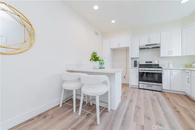 a kitchen with granite countertop a table chairs stove and cabinets