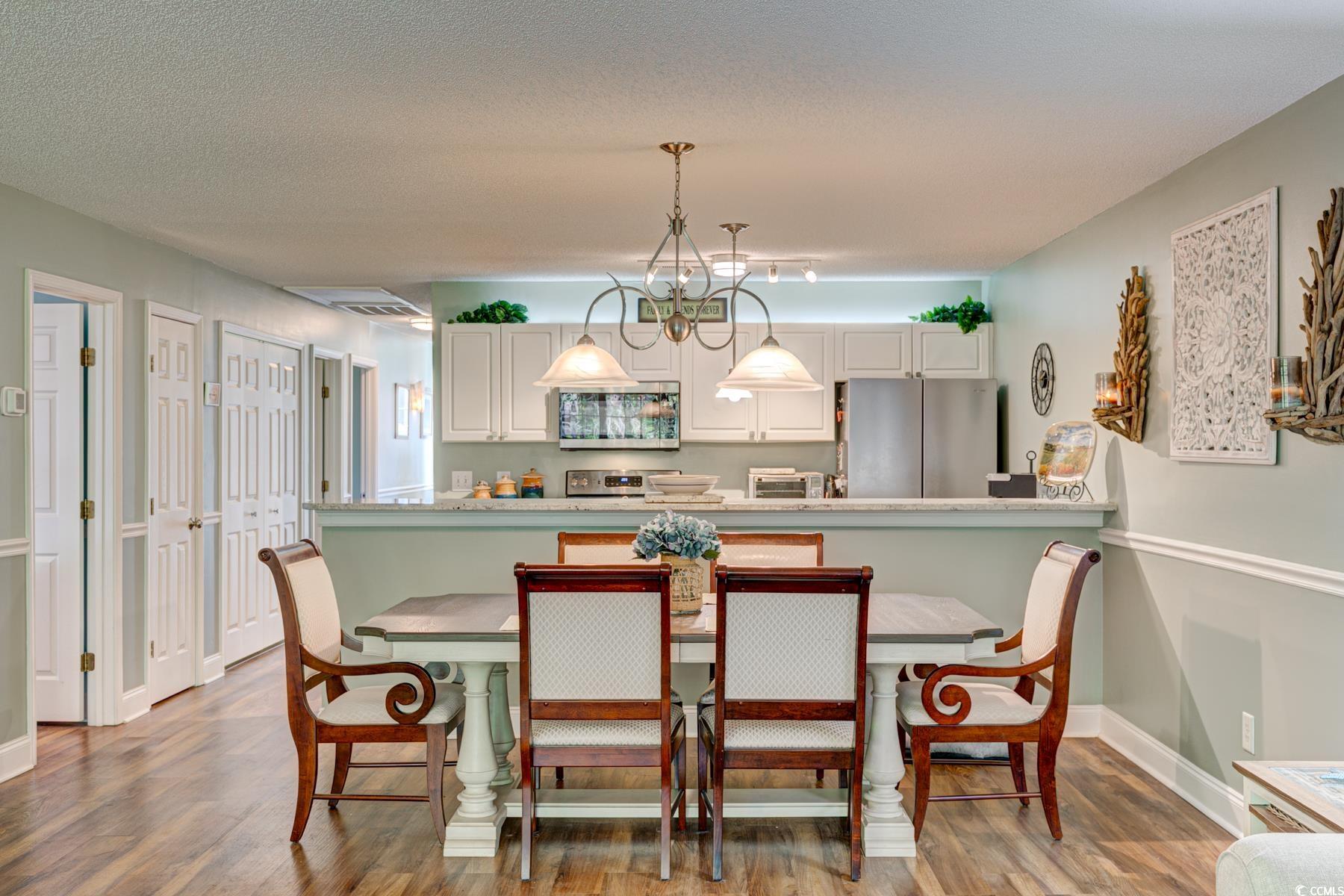 4840 Moss Creek Loop, Unit 36 Murrells Inlet, SC 29576 - Photo 17 of 37 Kitchen with appliances with stainless steel finishes, hanging light fixtures, white cabinetry, light wood finished floors, and a chandelier