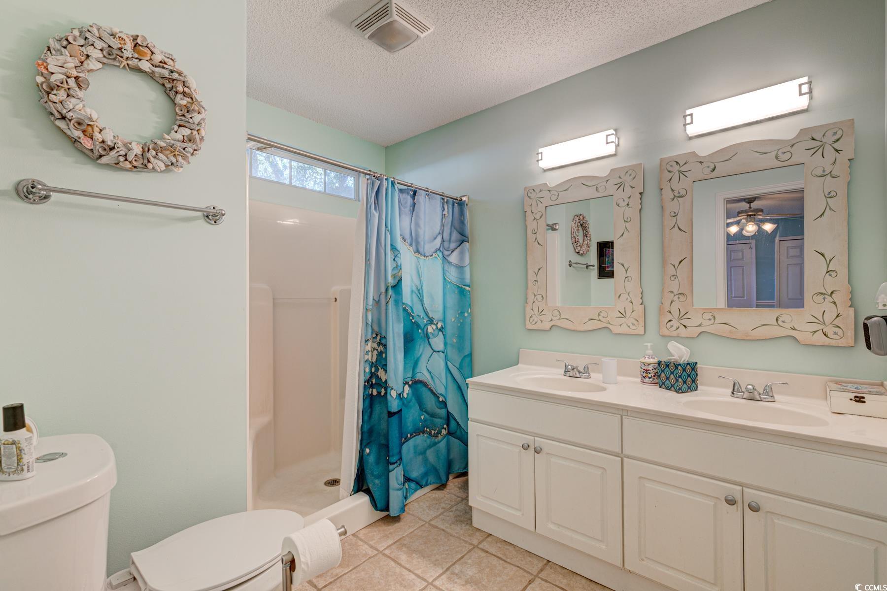 4840 Moss Creek Loop, Unit 36 Murrells Inlet, SC 29576 - Photo 26 of 37 Full bathroom featuring a textured ceiling, a stall shower, double vanity, and light tile patterned floors