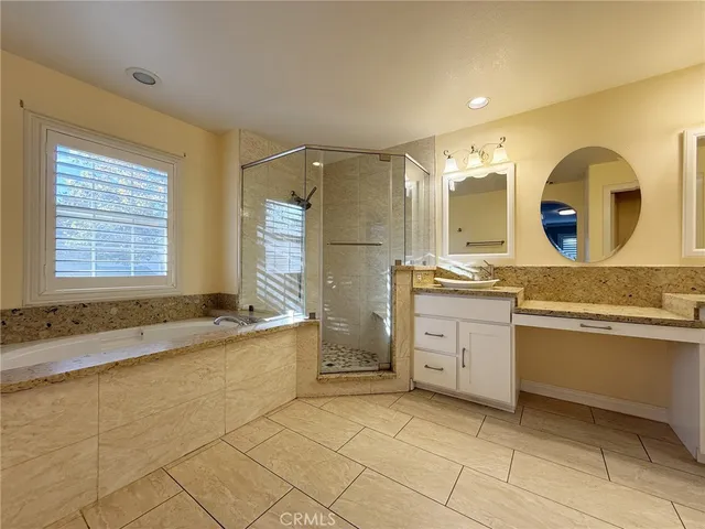 a spacious bathroom with a granite countertop sink mirror and a bathtub