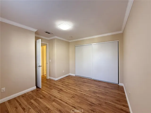 a view of an empty room with wooden floor and closet