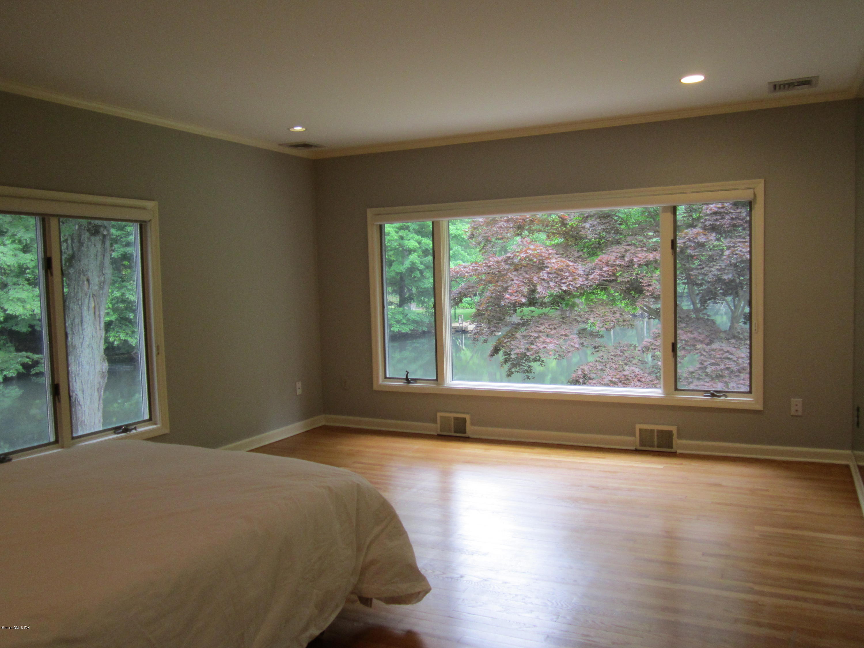 67 Burning Tree Road Greenwich, CT 06830 - Photo 12 of 28 a bedroom with a bed and wooden floor