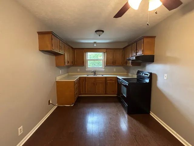 a kitchen with granite countertop a sink cabinets and wooden floor