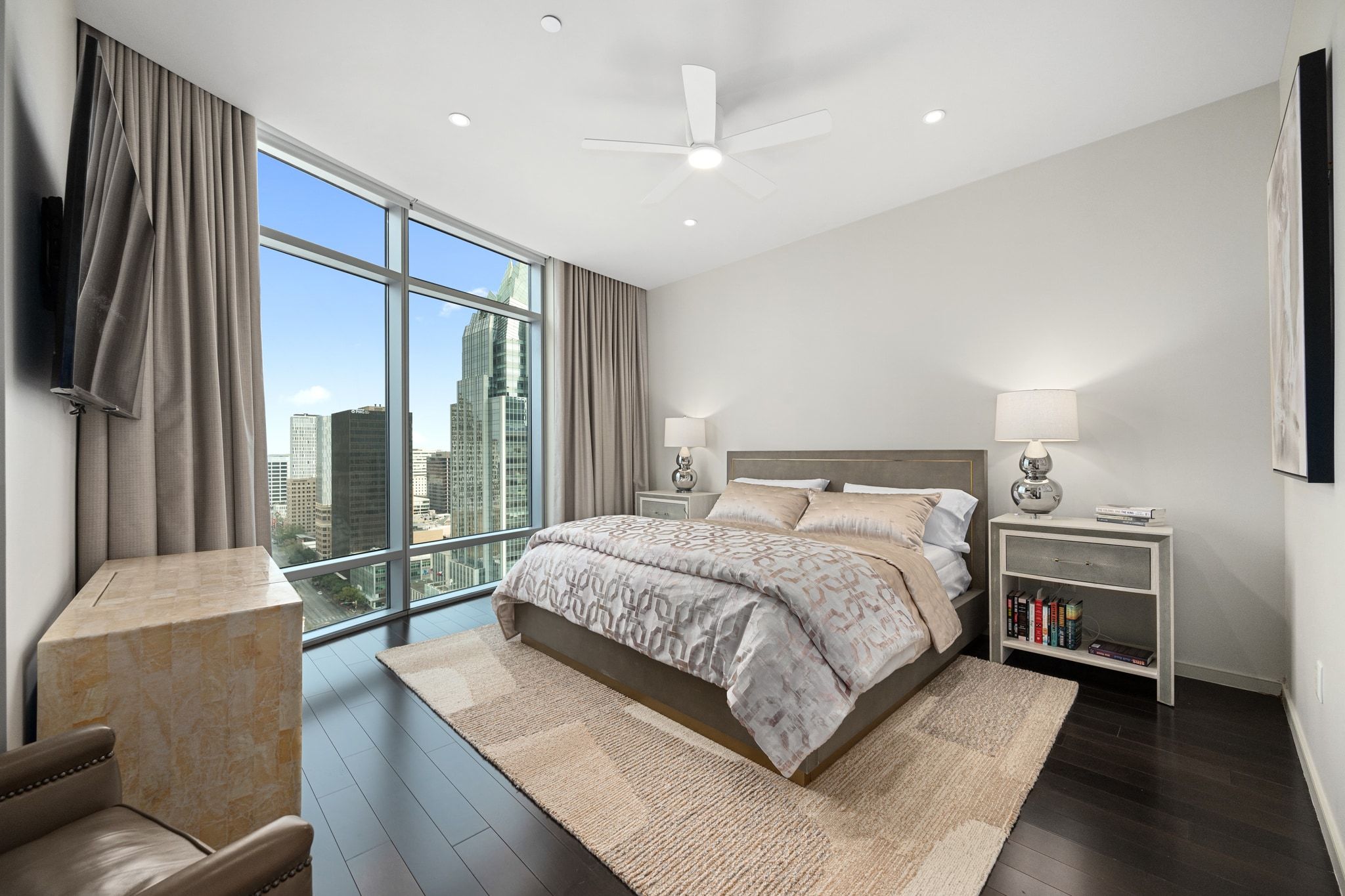 200 Congress Avenue, Unit 24E Austin, TX 78701 - Photo 16 of 40 a spacious bedroom with a large bed and a chandelier