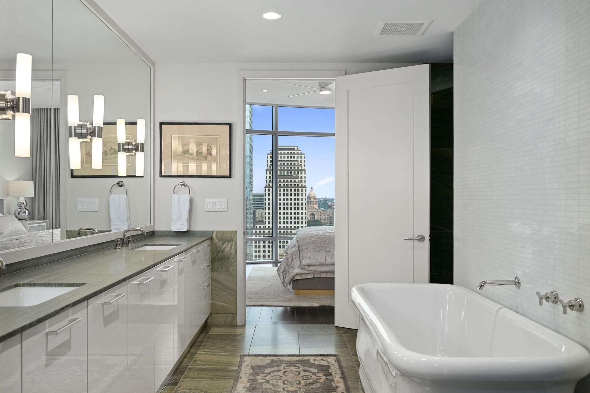 200 Congress Avenue, Unit 24E Austin, TX 78701 - Photo 20 of 40 a bathroom with a granite countertop sink a toilet a mirror and bathtub