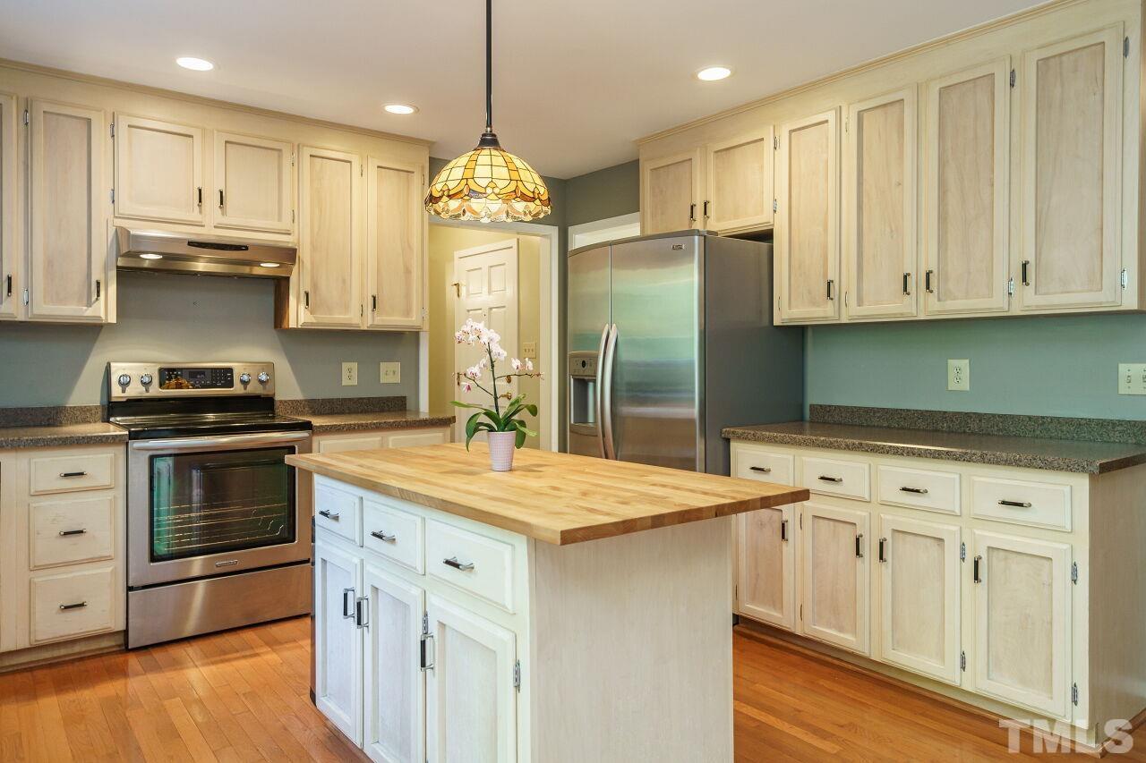 12213 Galway Drive Raleigh, NC 27613 - Photo 14 of 31 a kitchen with stainless steel appliances granite countertop a sink a stove a refrigerator and island with wooden floor