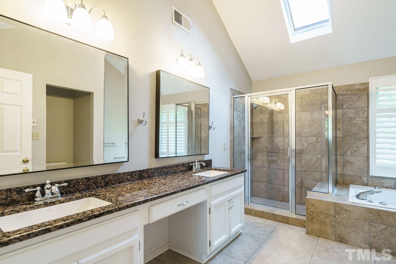 12213 Galway Drive Raleigh, NC 27613 - Photo 22 of 31 a bathroom with a granite countertop double vanity sink a mirror and a bathtub