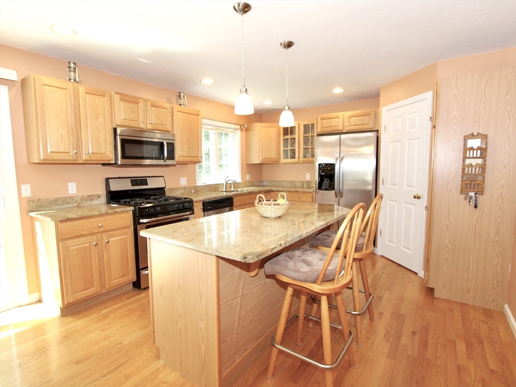 159 Mower Street Worcester, MA 01602 - Photo 6 of 27 a kitchen with stainless steel appliances granite countertop a stove top oven a sink a refrigerator with a dining table and chairs with wooden floor
