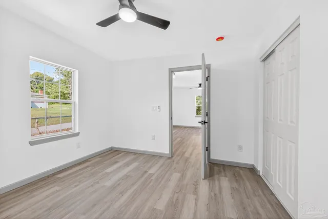 an empty room with wooden floor cabinet and windows