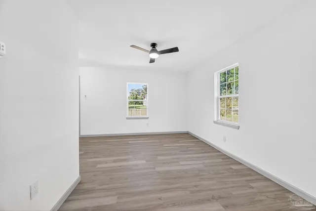 an empty room with windows and a ceiling fan