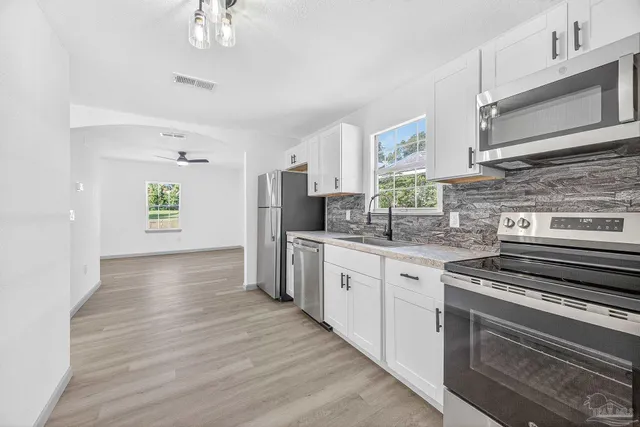 a kitchen with stainless steel appliances a stove cabinets and wooden floor