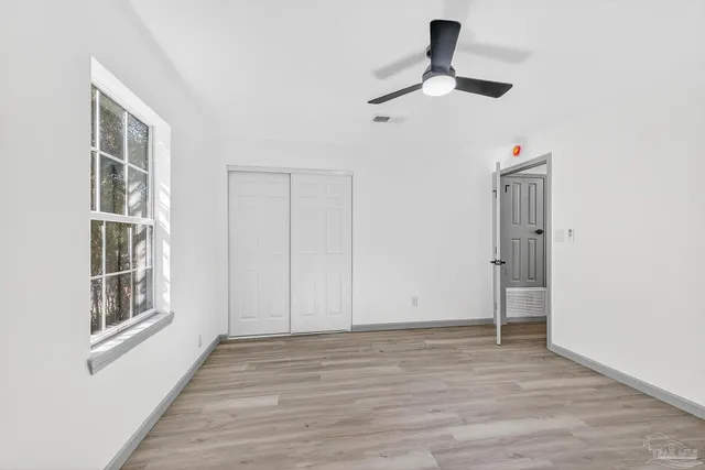 a view of empty room with wooden floor and fan