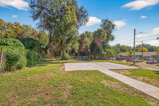 a view of yard with swimming pool outdoor seating and covered with trees