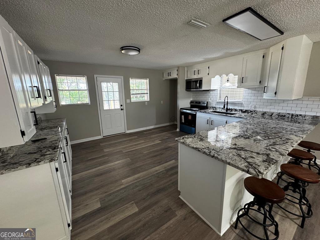 5781 Adams Road Valdosta, GA 31601 - Photo 19 of 27 a kitchen with granite countertop a sink stove and cabinets