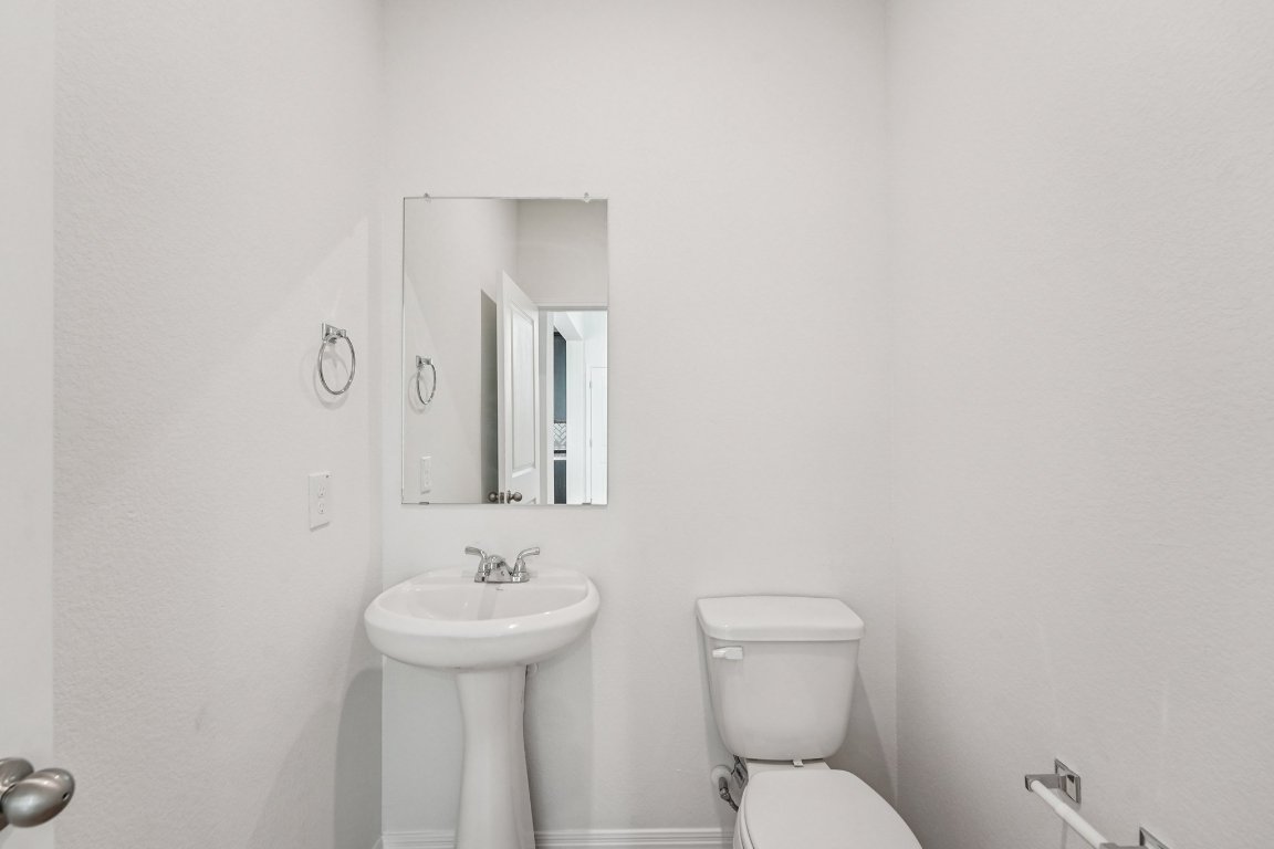 6309 Marsh Lane Buda, TX 78610 - Photo 15 of 39 a bathroom with a toilet a sink and mirror