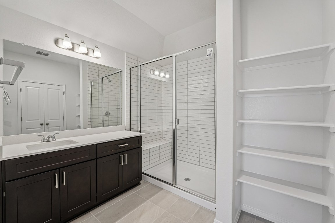 6309 Marsh Lane Buda, TX 78610 - Photo 24 of 39 a bathroom with a double vanity sink a large mirror and a shower
