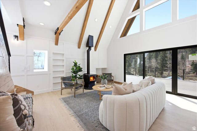 1833 Pine Loop Road Coalville, UT 84017 - Photo 4 of 26 Living area featuring an exposed beam vaulted ceiling, a freestanding wood-burning stove, large windows, sliding glass doors, and light wood-finish flooring