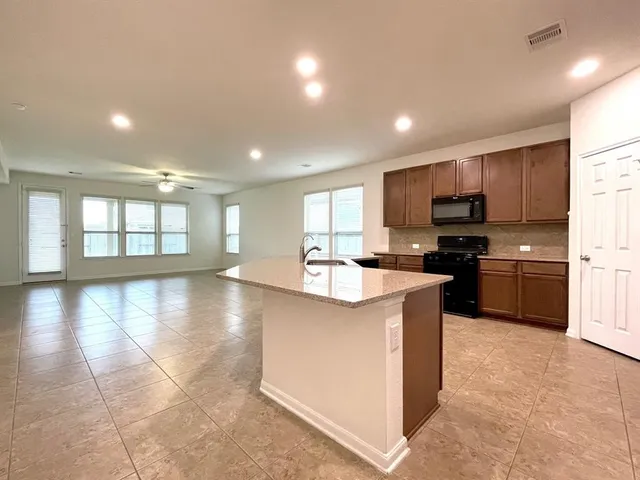 a large kitchen with granite countertop a large counter top stainless steel appliances and cabinets