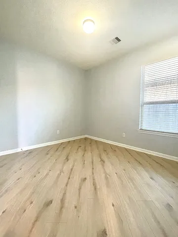 a view of empty room with wooden floor and fan