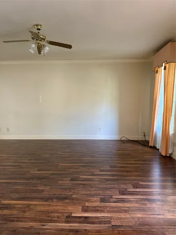 a view of a room with wooden floor and a ceiling fan