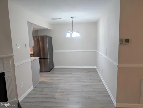 a view of a refrigerator in kitchen and an empty room